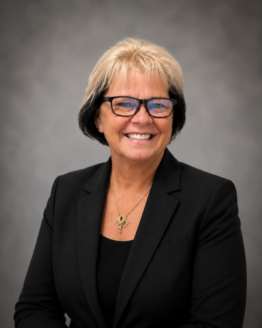 Smiling woman with glasses wearing black blazer