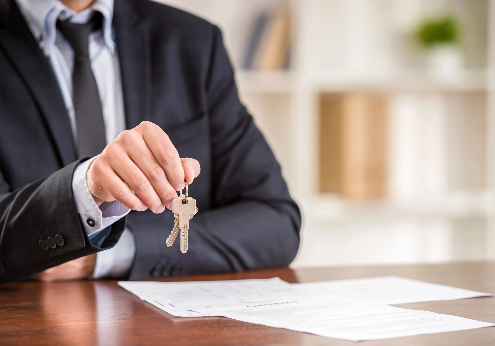 Person in suit handing house keys over contract
